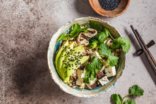 Foto Buckwheat noodles - soba with tofu, broccoli, avocado, seedlings and cilantro, top view, copy space