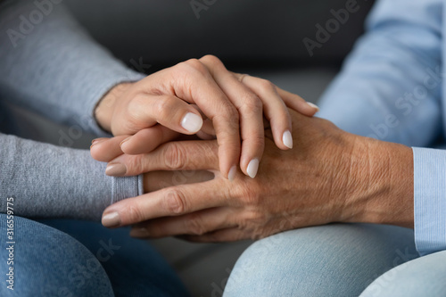 Close up granddaughter comforting grandmother, holding hands, expressing love