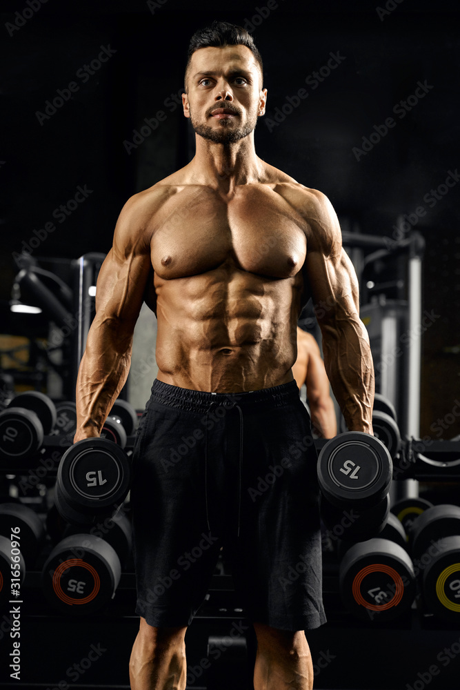 Pumped male bodybuilder holding dumbbells. Pumped male bodybuilder holding dumbbells.