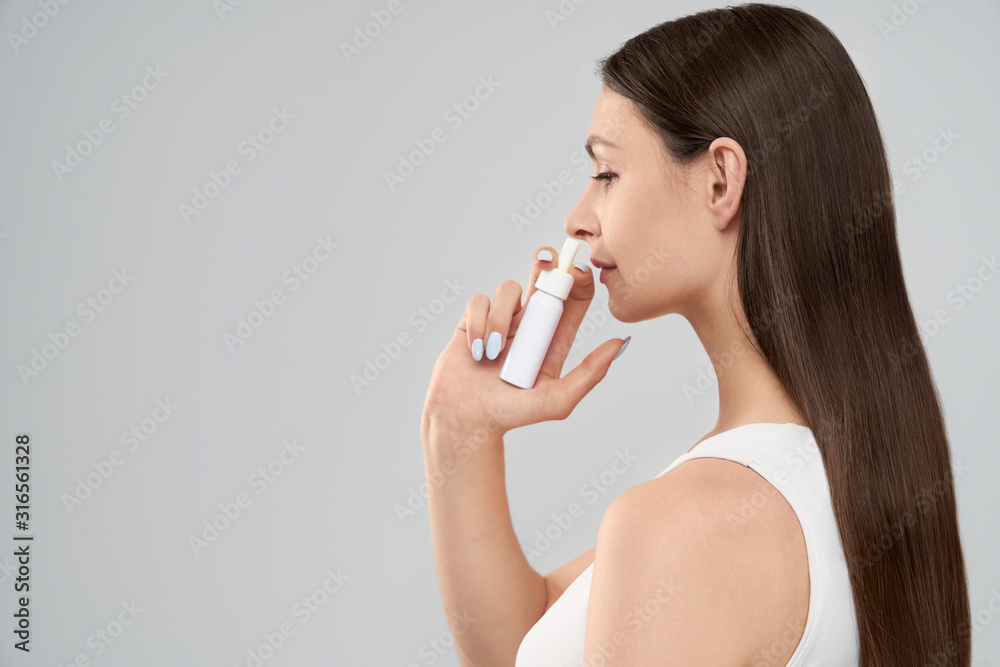 Woman using spray for runny nose. Woman using spray for runny nose.