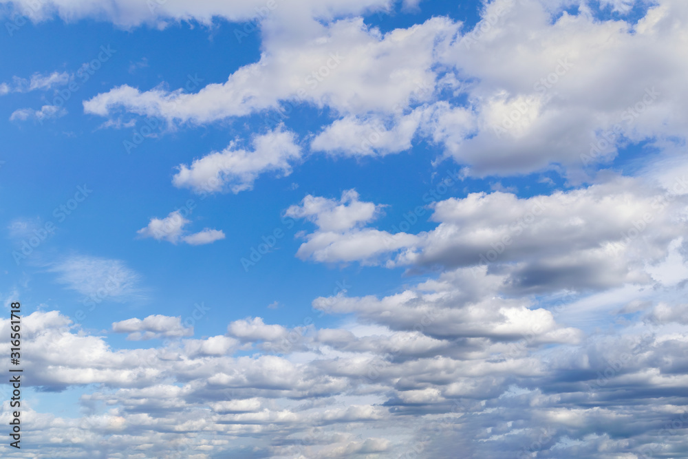 Blue summer sky with bright white cumulus clouds.