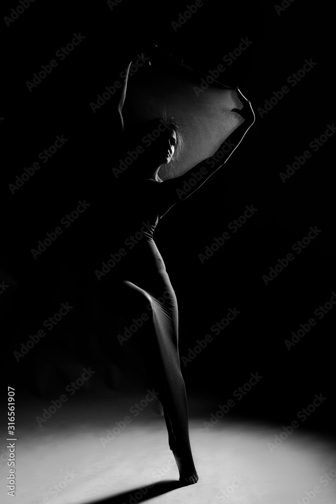 Slim girl wearing a white bodysuit dances a modern avant garde dance, covering her body with elastic transparent fabric. Artistic, conceptual, monochrome and creative design. Silhouette  photography.