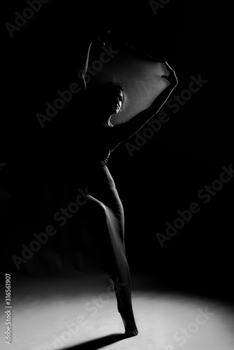 Slim girl wearing a white bodysuit dances a modern avant garde dance, covering her body with elastic transparent fabric. Artistic, conceptual, monochrome and creative design. Silhouette  photography. © Алексей Торбеев