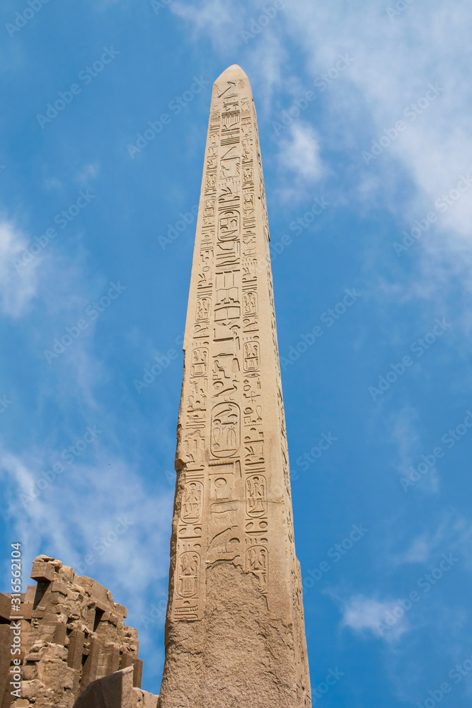 Karnak temple complex in Luxor, Egypt. Ancient stella with hieroglyphs. Blue sky with clouds,