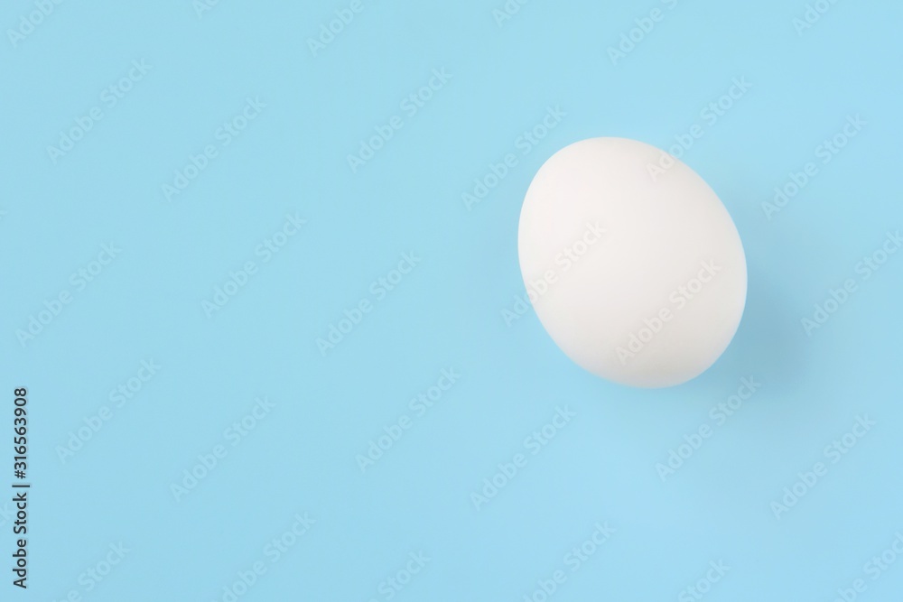 White chicken egg for Easter holiday on neutral light blue background. Raw organic egg. Easter eggs. Ingredients for healthy protein breakfast. Keto diet. Easter background traditional symbol White chicken egg for Easter holiday on neutral light blue background. Raw organic egg. Easter eggs. Ingredients for healthy protein breakfast. Keto diet. Easter background traditional symbol