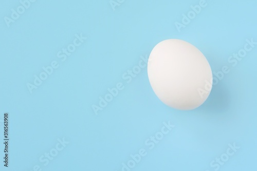 White chicken egg for Easter holiday on neutral light blue background. Raw organic egg. Easter eggs. Ingredients for healthy protein breakfast. Keto diet. Easter background traditional symbol