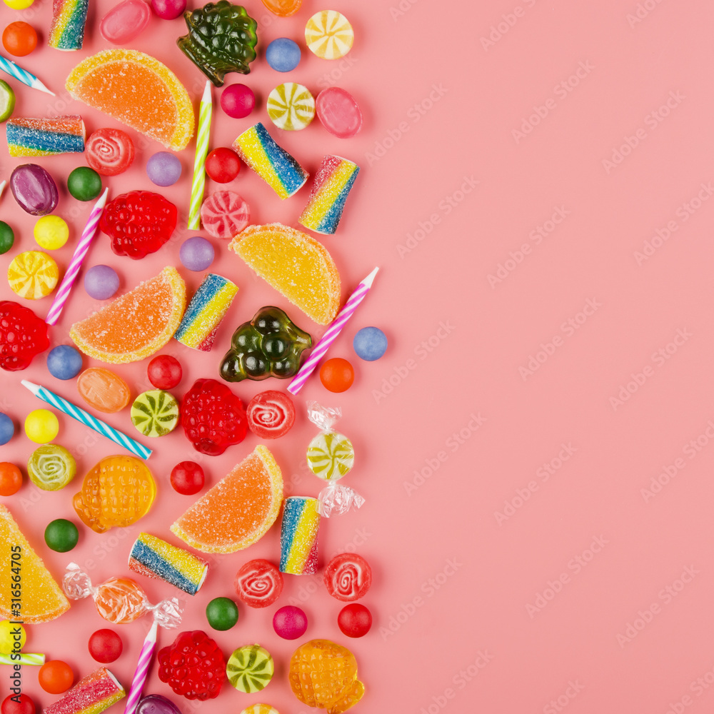 Flat lay view at sweet background of different type color and taste candies and birthday candles on pink. Space for text Flat lay view at sweet background of different type color and taste candies and birthday candles on pink. Space for text