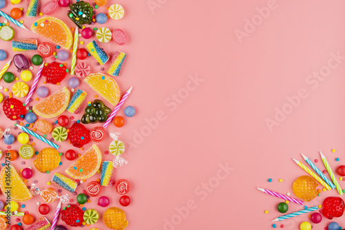 Flat lay view at sweet background of different type color and taste candies and birthday candles on pink. Space for text © Mikhailov Studio