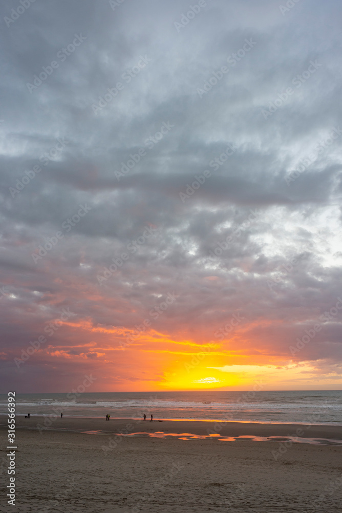 France. Picardie. Fort-Mahon. Des personnes sur une plages se promènent. Coucher de soleil sur une plage de sable à marée basse. People on a beach are walking. Sunset on a sandy beach at low tide. France. Picardie. Fort-Mahon. Des personnes sur une plages se promènent. Coucher de soleil sur une plage de sable à marée basse. People on a beach are walking. Sunset on a sandy beach at low tide.