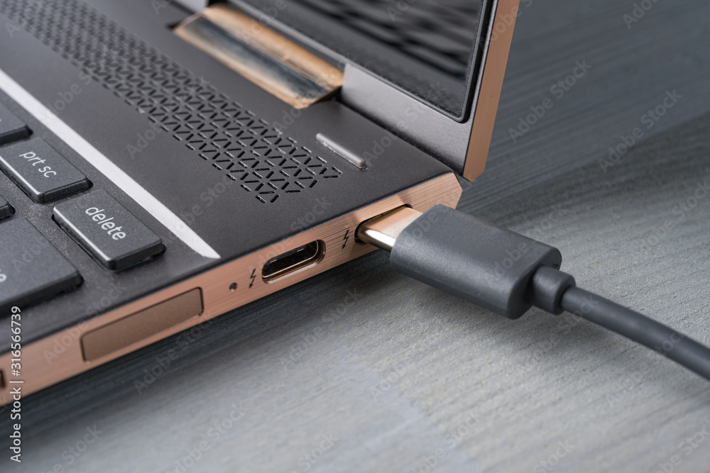 Closeup of USB Type C grey cable being connected to the laptop computer.