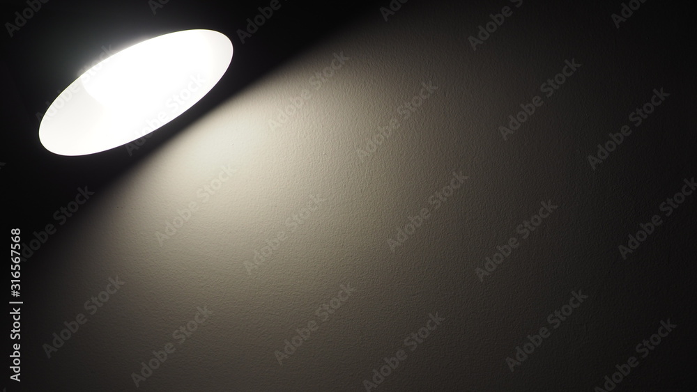 Desk lamp shining warm light in the dark room on the wall with copy space for add text. Living, home and office interior concept Desk lamp shining warm light in the dark room on the wall with copy space for add text. Living, home and office interior concept