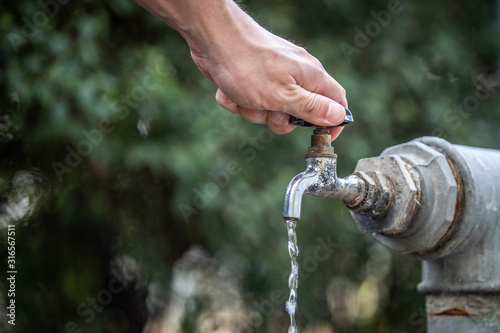 A man tries to open a tap water. photo