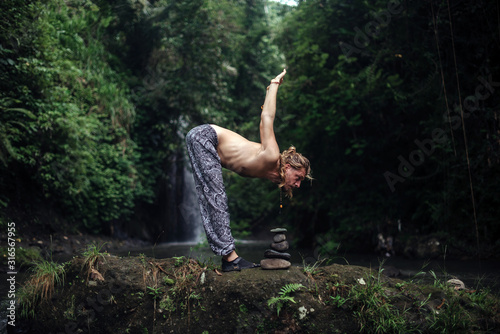 Yoga practice and meditation in nature. Man practicing near river