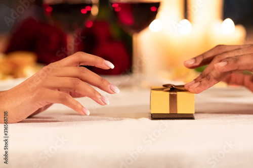 Male Hands Pushing Gift Box To Girlfriend On Restaurant Table