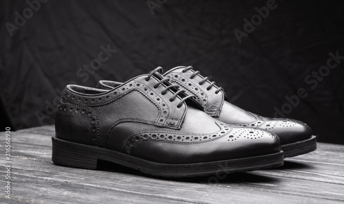 Black leather shoes against wooden background.