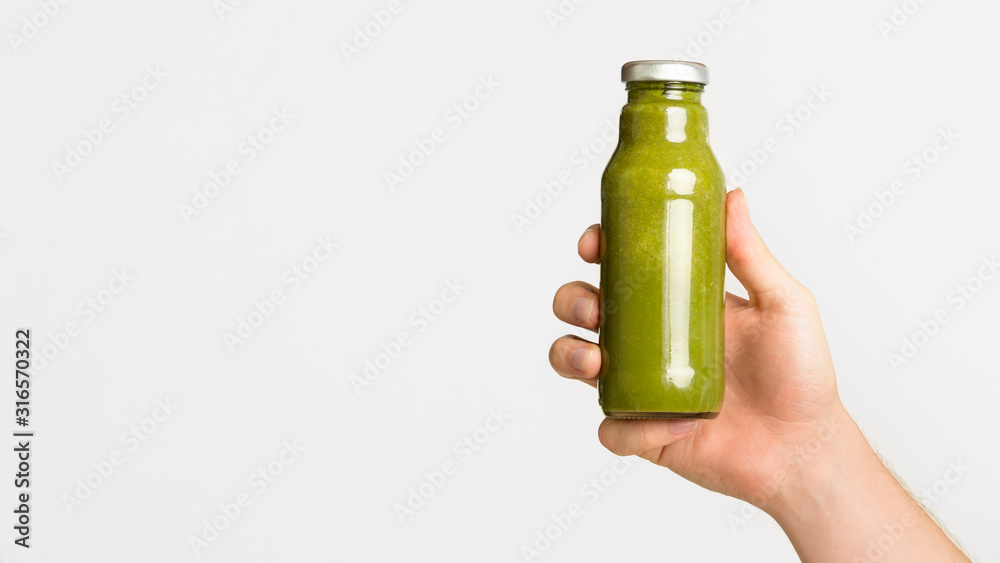Female hand holding vegetable detox smoothie on white Female hand holding vegetable detox smoothie on white