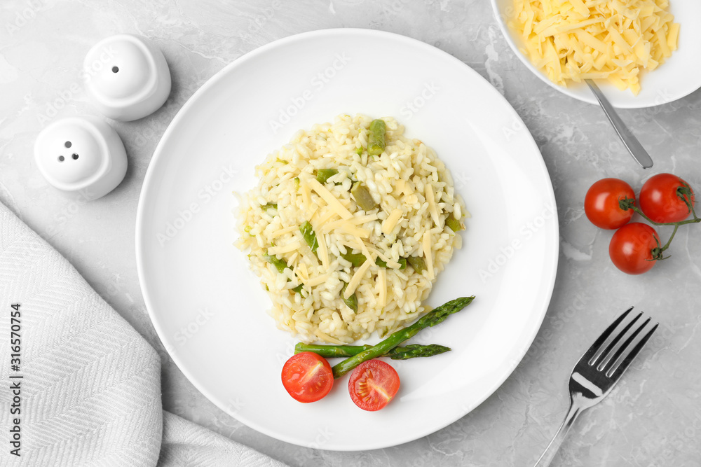 Delicious risotto with asparagus and tomatoes on grey marble table, flat lay Delicious risotto with asparagus and tomatoes on grey marble table, flat lay