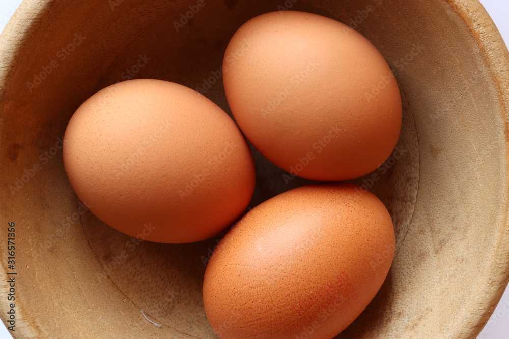 Photography of three eggs in a wooden bowl for food background Photography of three eggs in a wooden bowl for food background