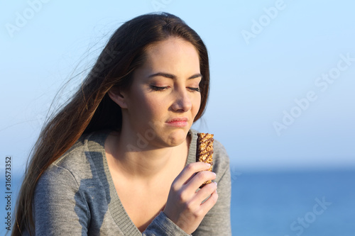 Disgusted woman tasting a bad energy bar