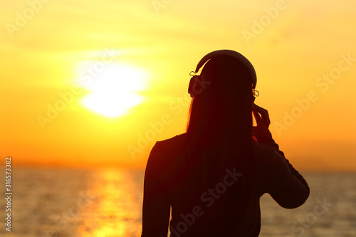 Girl wearing headphones listening to music at sunset photo