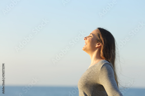 Happy woman breathing fresh air and heating on the beach