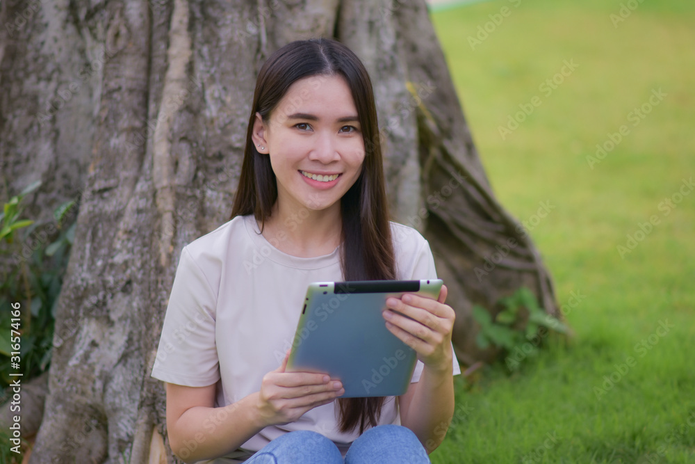 Beauty women using tablet reading E-book sitting in city park morning fresh Beauty women using tablet reading E-book sitting in city park morning fresh