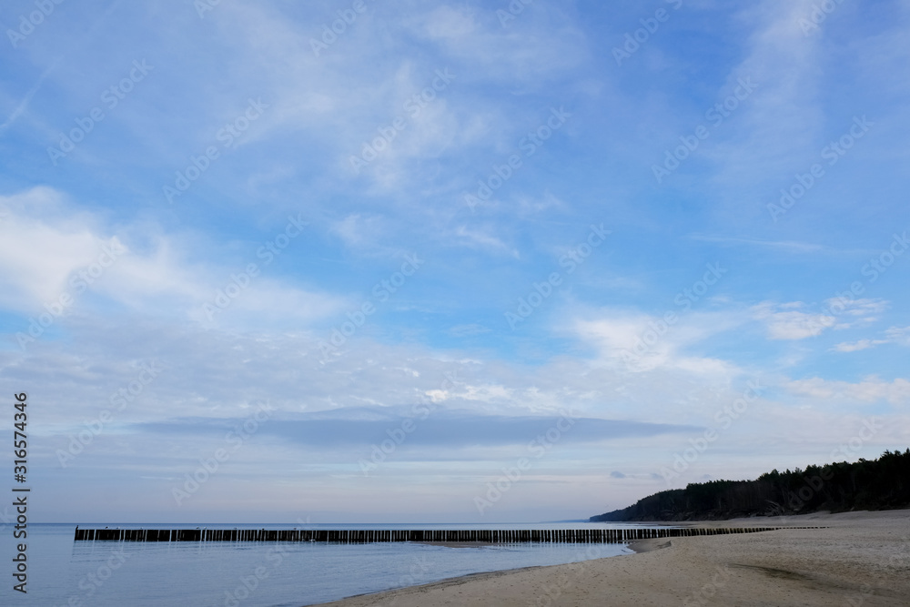 A beach with breakwaters in Dziwnowek / Poland on the Baltic Sea in the fall after the season. Empty beach after season. A beach with breakwaters in Dziwnowek / Poland on the Baltic Sea in the fall after the season. Empty beach after season.