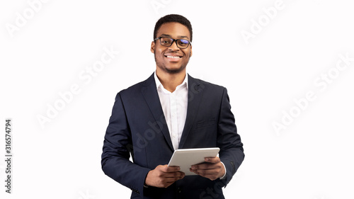 Smiling black guy standing with tablet at studio photo