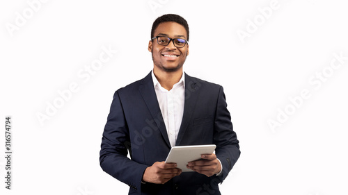 Smiling black guy standing with tablet at studio