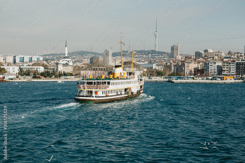 A ferry sailing against the backdrop of urban architecture in Istanbul. Traditional public water transport