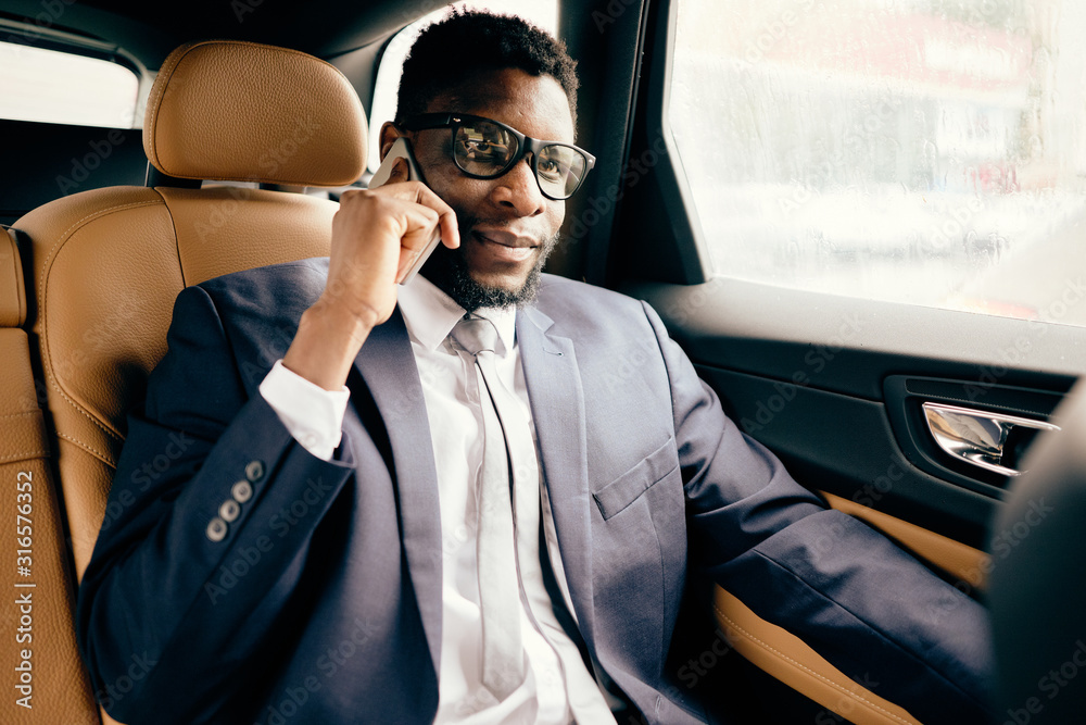 Businessman sits in the car and has conversation on the phone.