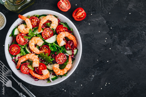 Shrimp salad with fresh green lettuce and radicchio leaves, cucumbers, tomatoes and sesame seeds.