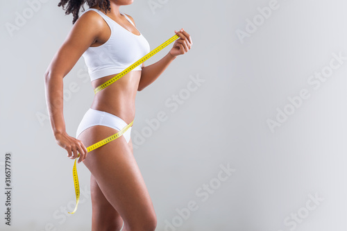 Fotografie, Tablou Afro girl in white underwear measuring her body