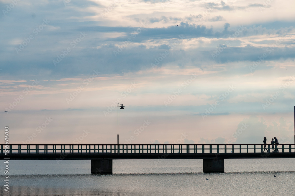 Suède. Sweden. La silhouette de trois personnes marchent sur une passerelle au dessus de la mer Baltique. Sweden. Sweden. The silhouette of three people walk on a footbridge over the Baltic Sea Suède. Sweden. La silhouette de trois personnes marchent sur une passerelle au dessus de la mer Baltique. Sweden. Sweden. The silhouette of three people walk on a footbridge over the Baltic Sea