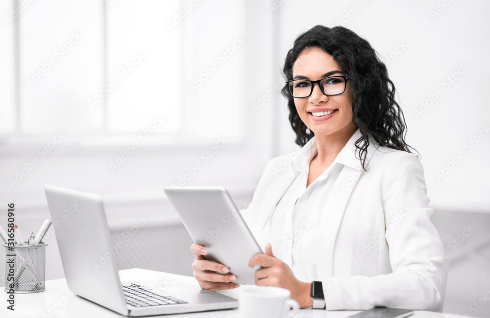 Portrait of happy latin girl using tablet and computer Portrait of happy latin girl using tablet and computer