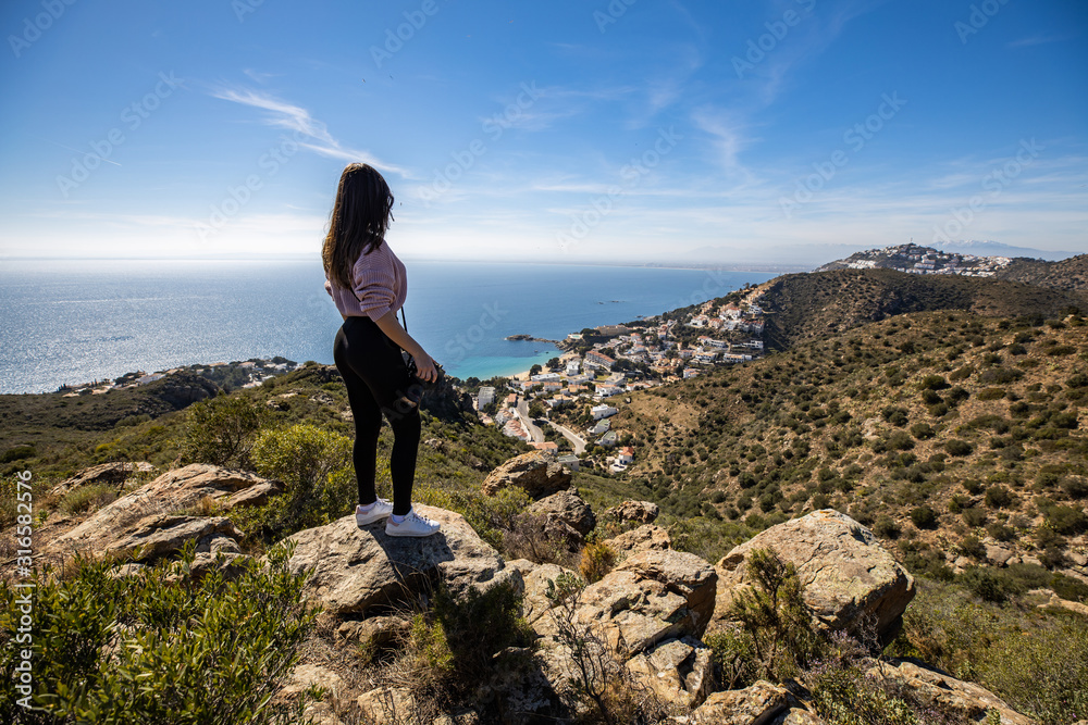 Beautiful woman photographer standing on a cliff holding a professional camera Beautiful woman photographer standing on a cliff holding a professional camera