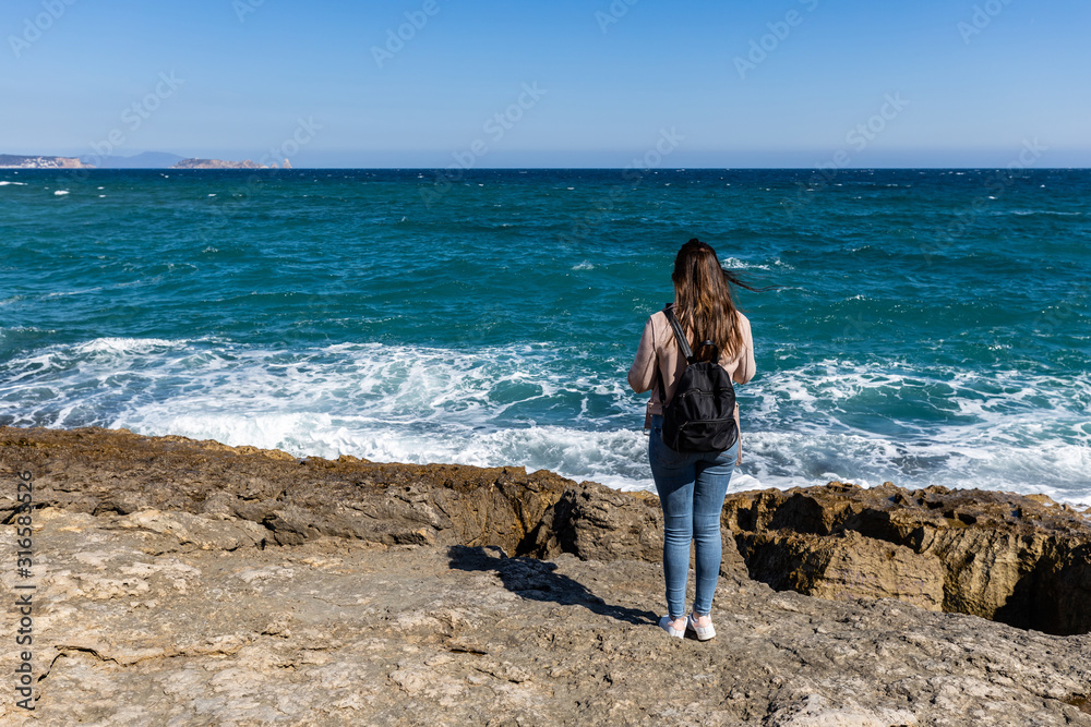 Beautiful woman standing on a cliff during sunset with the mediterranean sea in the background at Cap de Creus Beautiful woman standing on a cliff during sunset with the mediterranean sea in the background at Cap de Creus