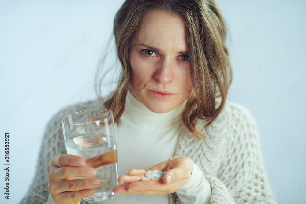 concerned woman with cup of water holding many pills concerned woman with cup of water holding many pills
