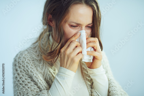 ill modern middle age housewife wiping nose with napkin