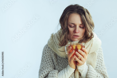 female holding cup of tea against winter light blue background