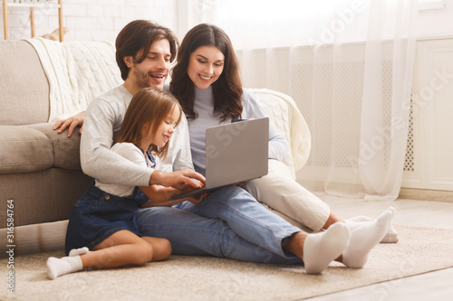 Happy family with daughter using laptop together at home
