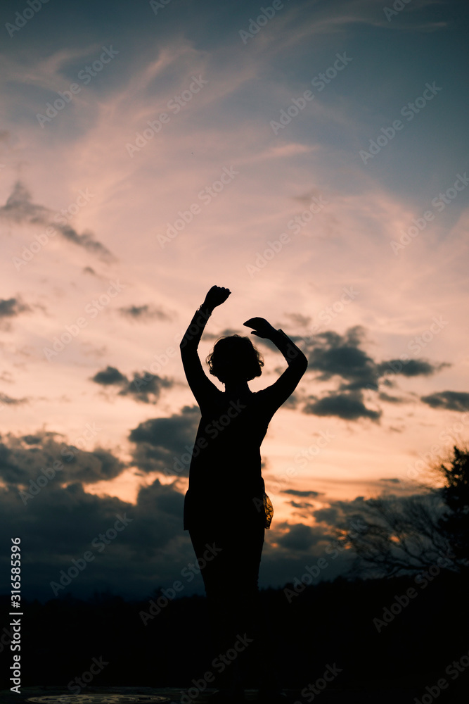 Silhouette of young woman against pink sky 