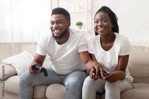 Black couple playing video games at home, competing with each other