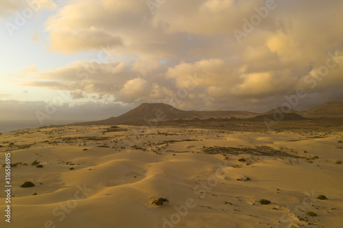 Desert volcano with sand dunes and golden sky