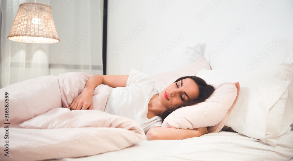 Safe and sound. Close-up photo of a gorgeous girl, who is sleeping in her bed on peach-colored sheets, while the lights are on. Safe and sound. Close-up photo of a gorgeous girl, who is sleeping in her bed on peach-colored sheets, while the lights are on.
