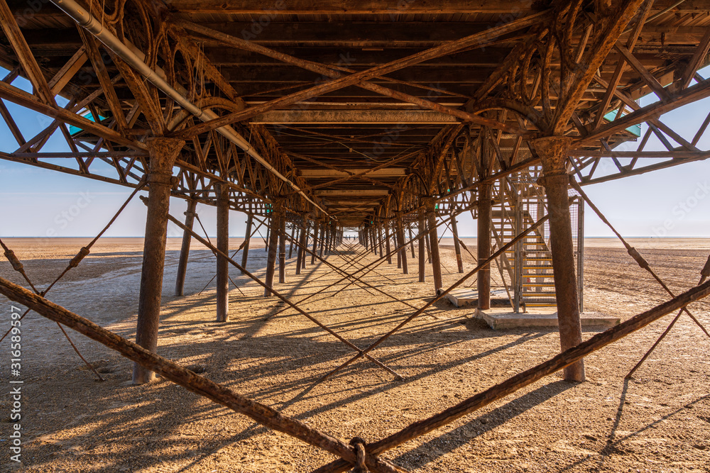 Naklejka premium Standing under the rusty iron construction on the downside of a pier