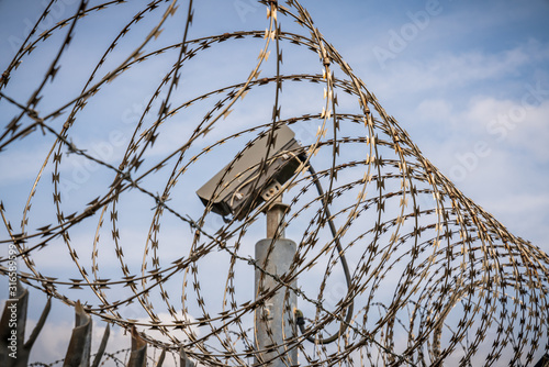 A barbwire fence with a surveillance camera