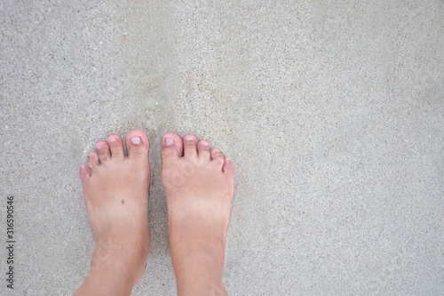 A female barefoot on sand beach with wet background and copy space