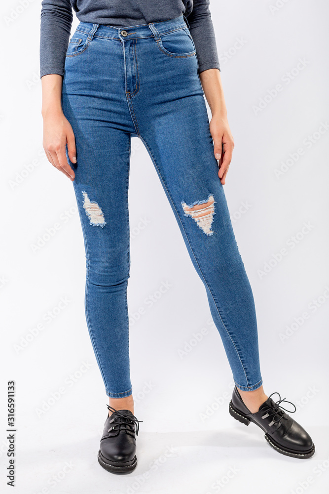 girl in jeans shows off jeans on white background close up, blue jeans