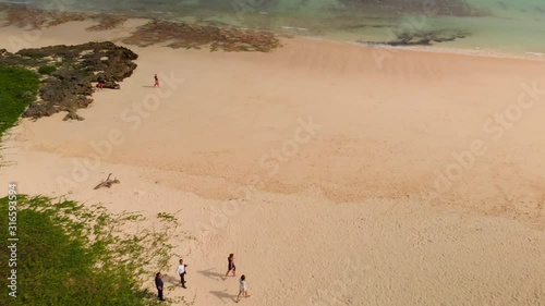 Aerial revealing shot of a tropical beach and turquoise water of the pacific. People walk along the beach. photo